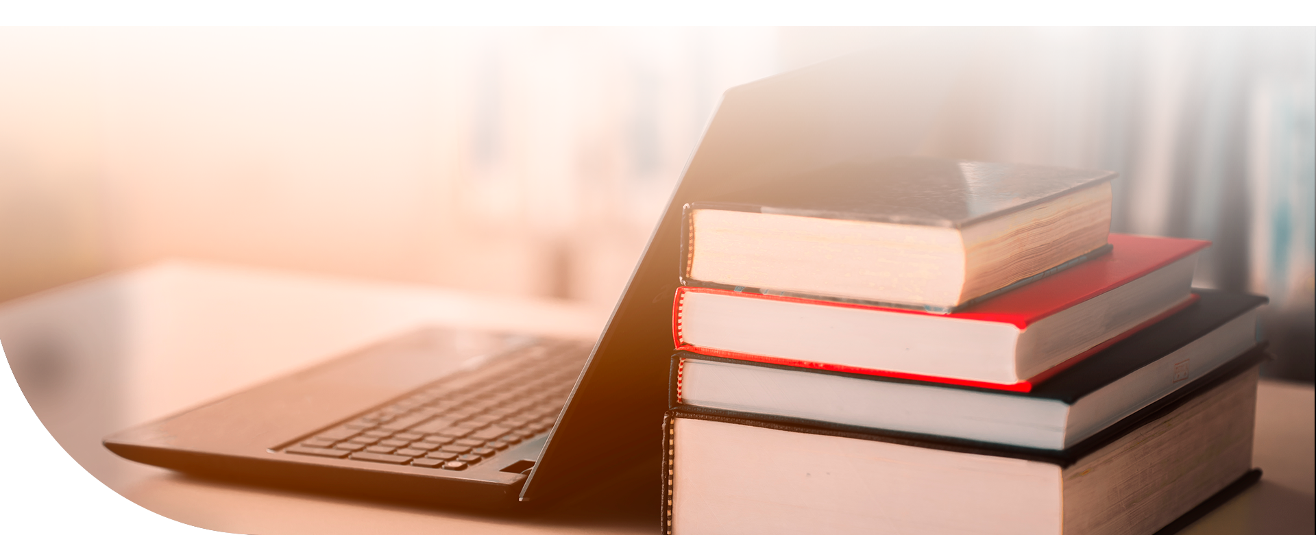 Una computadora y cuatro libros en un escritorio.