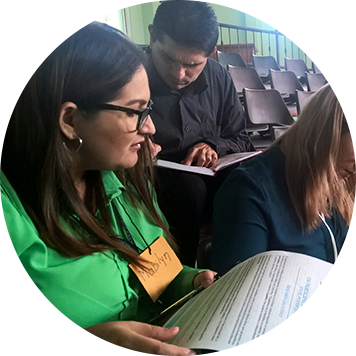 dos mujeres y un hombre, sentados revisando documentos.