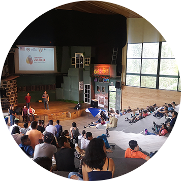 niños y jóvenes en un anfiteatro observando una presentación de dos hombres.