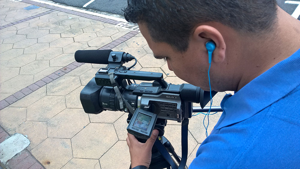 hombre con cámara de vídeo y audífonos grabando en la acera