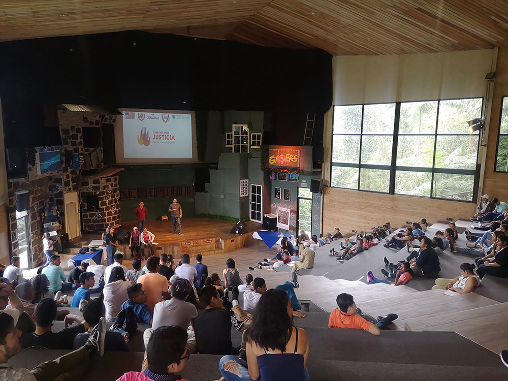 niños y jóvenes sentados viendo una presentación de dos hombres