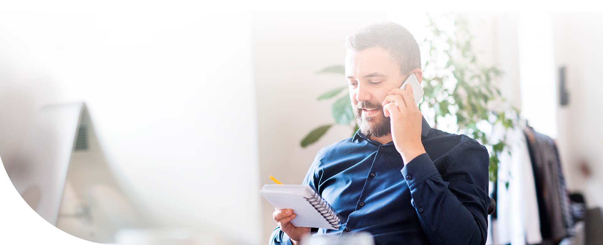 hombre sentado en la oficina, hablando por teléfono y viendo su agenda