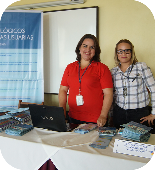 dos mujeres expositoras, hay una mesa, material informativo y un banner.
