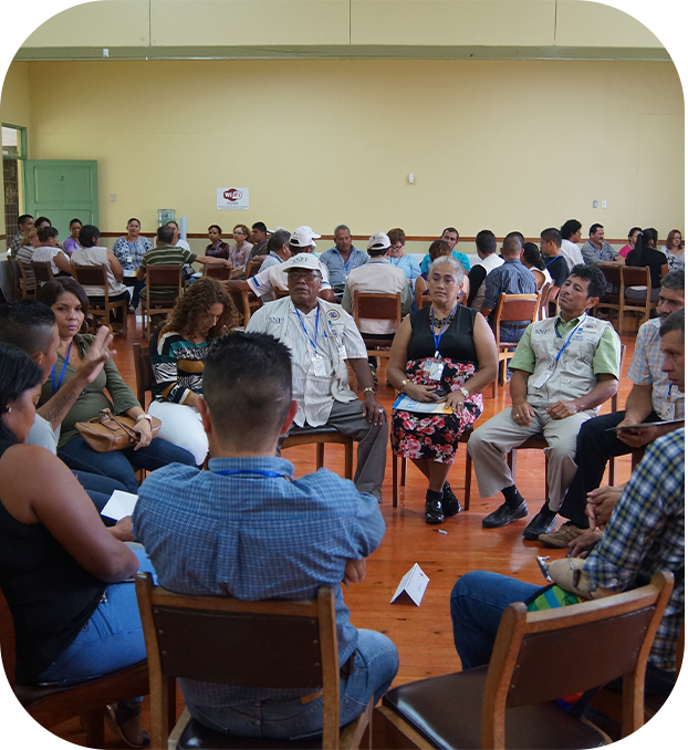 varias personas sentadas en sillas, formando circulos y conversando entre ellas.