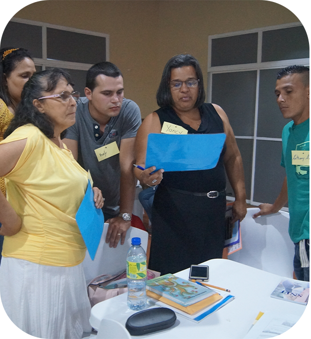 tres mujeres y dos hombres de pie, observando un documento.