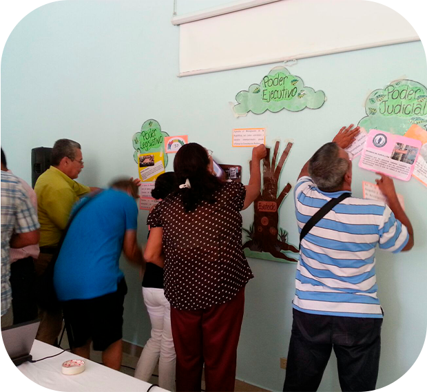 Hombres y mujeres colocando carteles en forma de árbol en una pared.