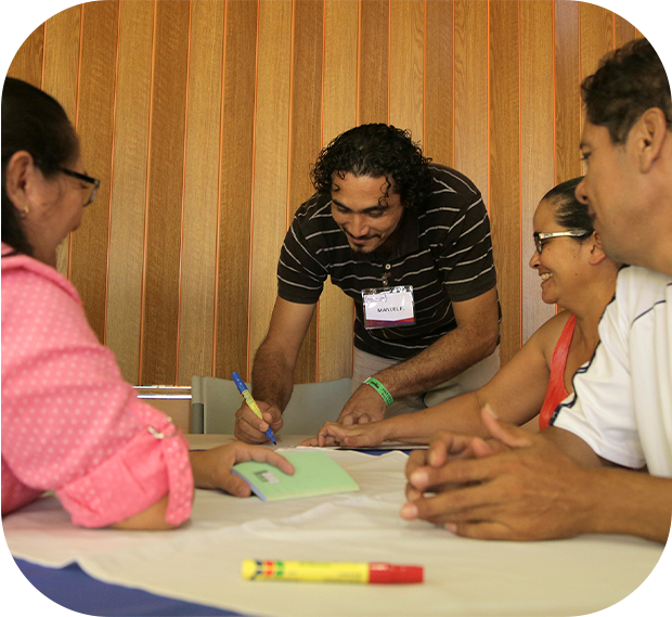 dos mujeres y dos hombres, conversando y escribiendo en una mesa.