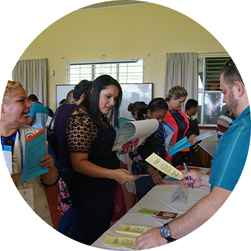 personas tomando información de un stand y conversando entre sí.