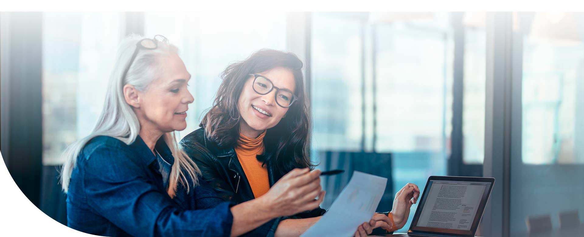 dos mujeres sentadas, observando un documento en la oficina